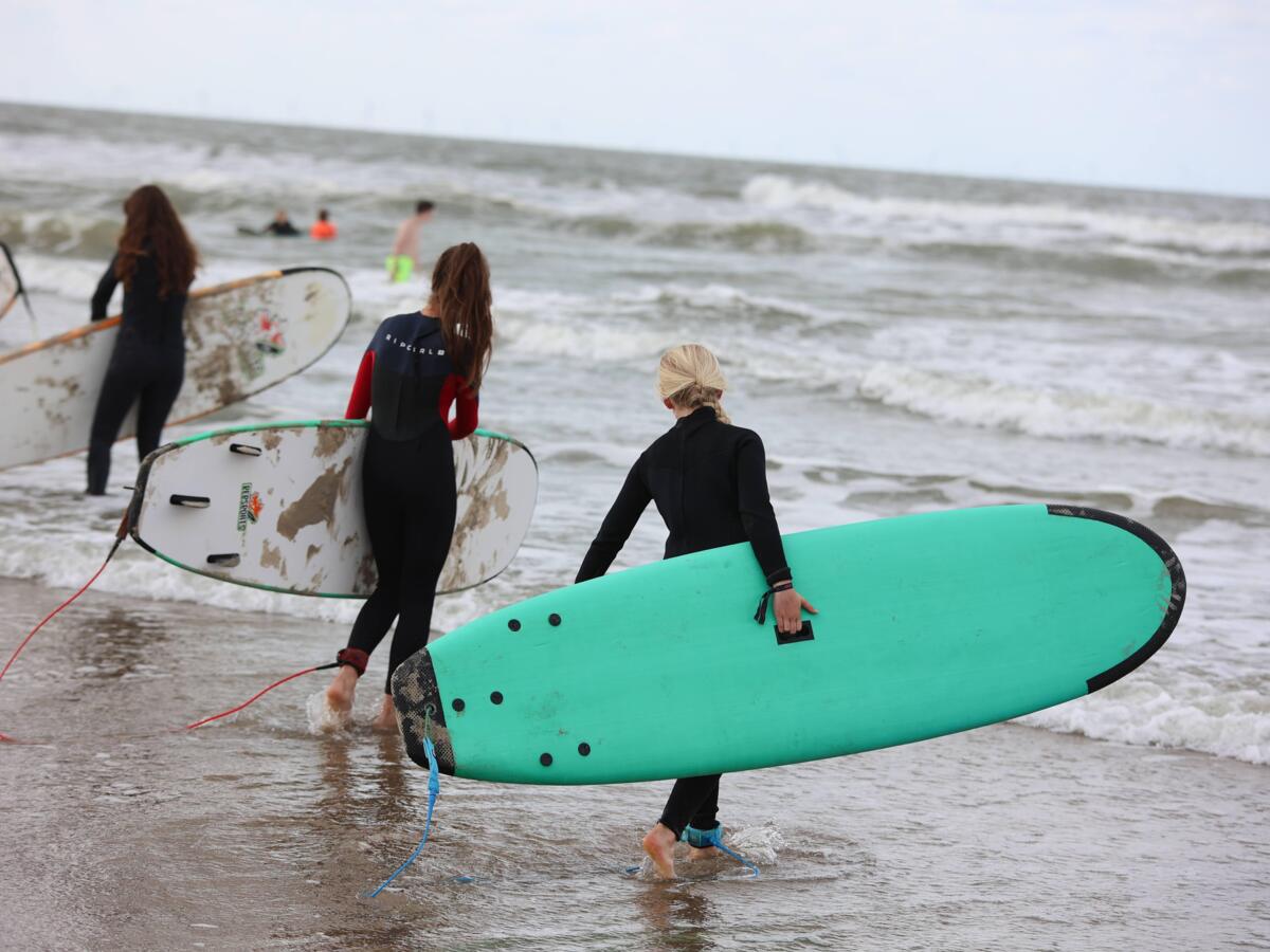 Surfen als actieve teambuilding tijdens een bedrijfsuitje op het strand.