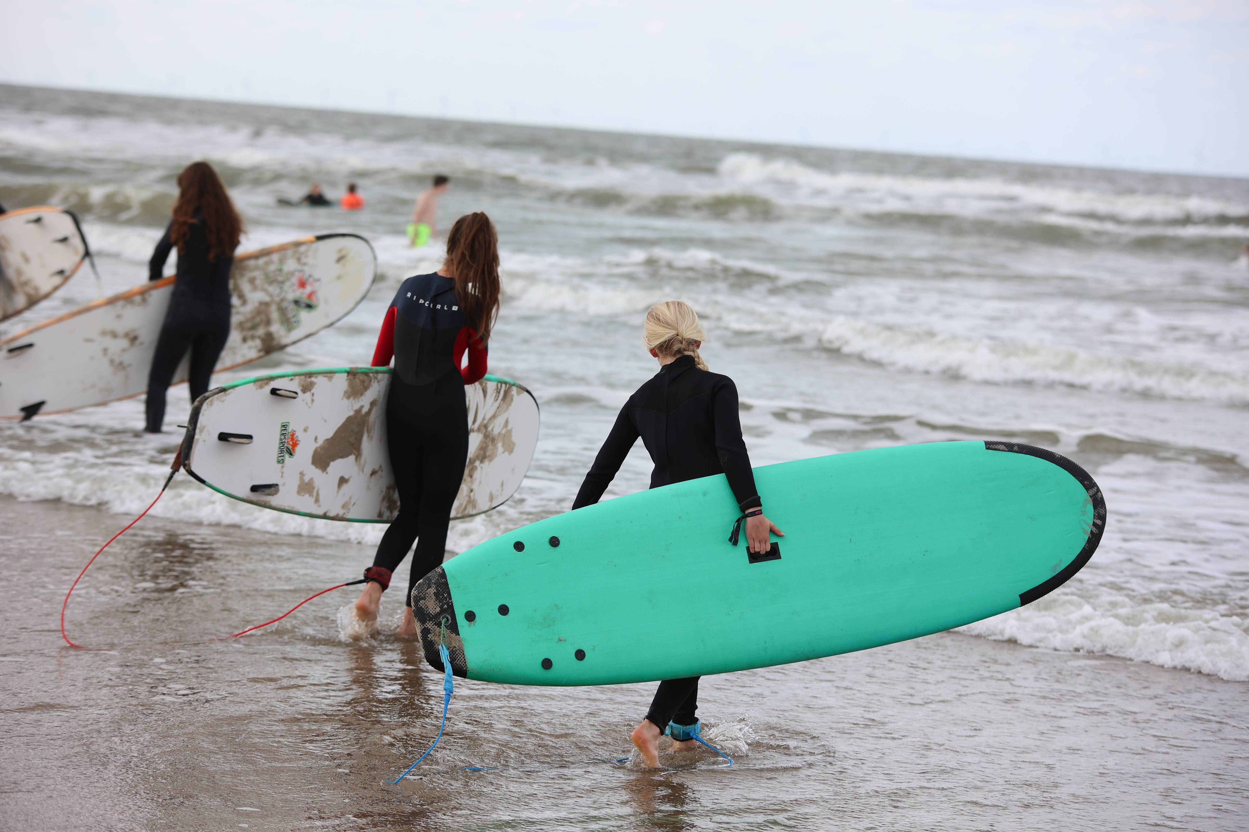 Surfen als actieve teambuilding tijdens een bedrijfsuitje op het strand.