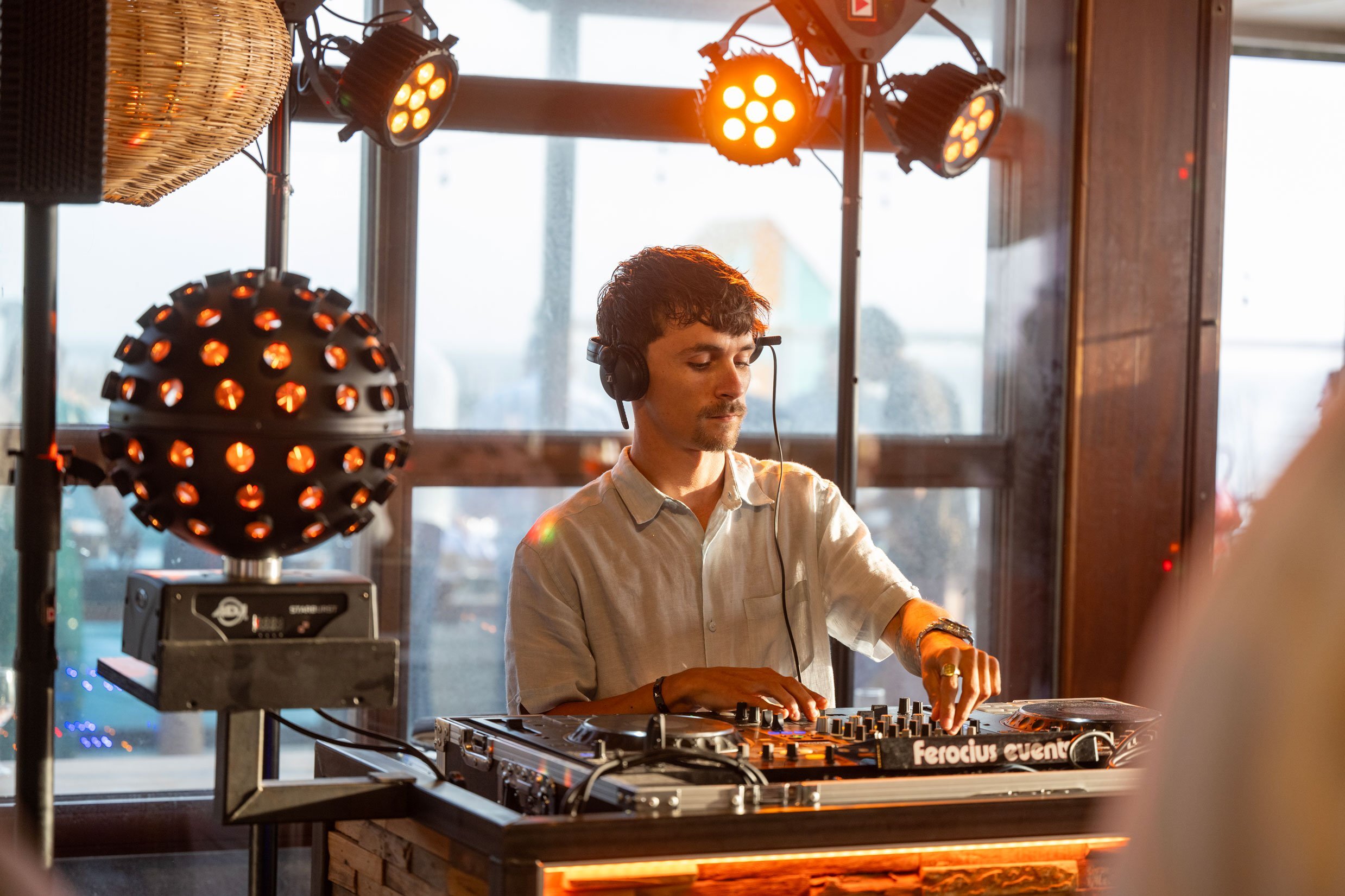 DJ draait muziek op een bruisend strandfeest bij zonsondergang.